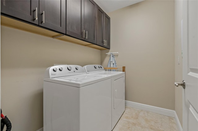 laundry area with cabinet space, light tile patterned floors, baseboards, and washer and clothes dryer