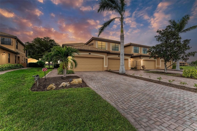 mediterranean / spanish home with a garage, a tiled roof, decorative driveway, stucco siding, and a front yard