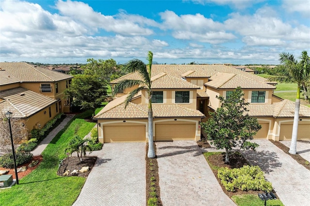 mediterranean / spanish home with a garage, decorative driveway, and stucco siding