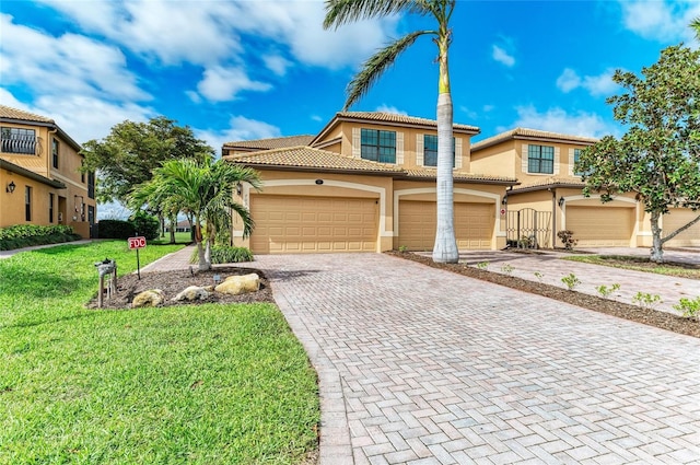 mediterranean / spanish-style house featuring a front yard, decorative driveway, a tile roof, and stucco siding