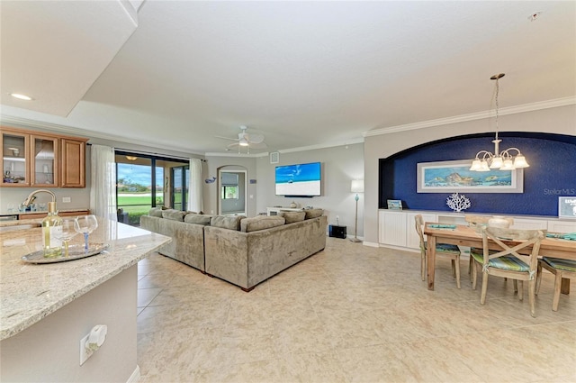 living room featuring crown molding, baseboards, and ceiling fan with notable chandelier