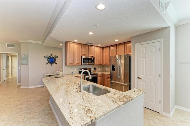 kitchen with stainless steel appliances, a peninsula, a sink, visible vents, and light stone countertops