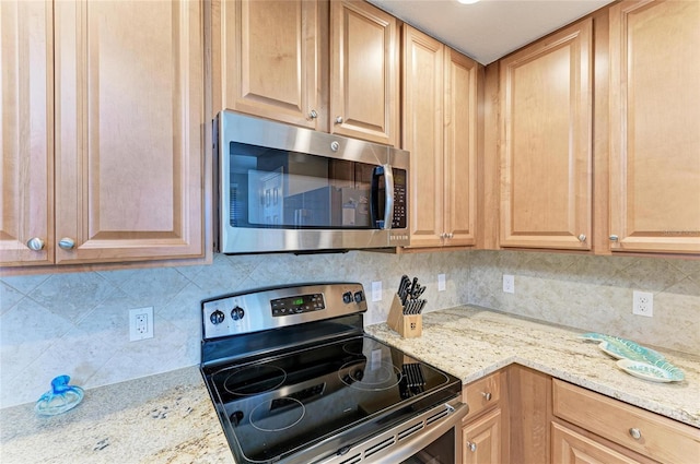 kitchen with light stone countertops, appliances with stainless steel finishes, decorative backsplash, and light brown cabinetry