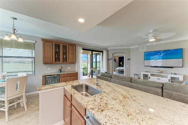 kitchen with open floor plan, ornamental molding, wine cooler, and a sink