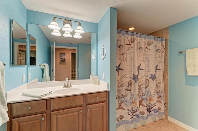 full bath featuring a textured wall, vanity, a shower with curtain, baseboards, and tile patterned floors