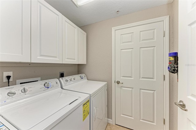 clothes washing area featuring a textured ceiling, cabinet space, and washer and dryer