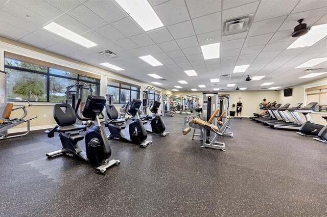 gym with a paneled ceiling, visible vents, and baseboards