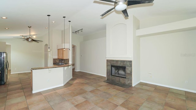 kitchen featuring freestanding refrigerator, open floor plan, ceiling fan, and a tile fireplace