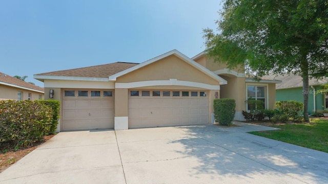 view of front of house with concrete driveway, an attached garage, and stucco siding