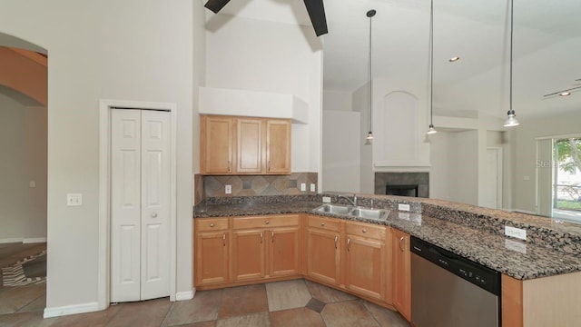 kitchen with a sink, stainless steel dishwasher, dark stone counters, tasteful backsplash, and pendant lighting