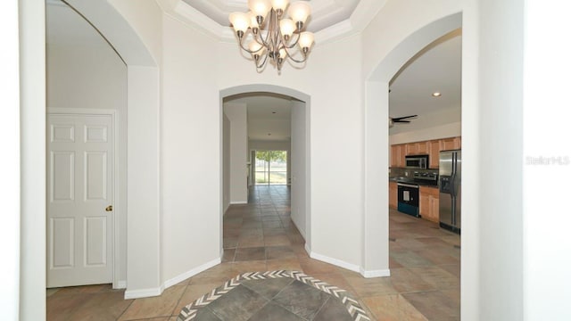 corridor with arched walkways, light tile patterned floors, a notable chandelier, baseboards, and ornamental molding