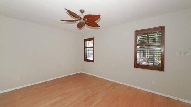 empty room with ceiling fan, wood finished floors, and baseboards