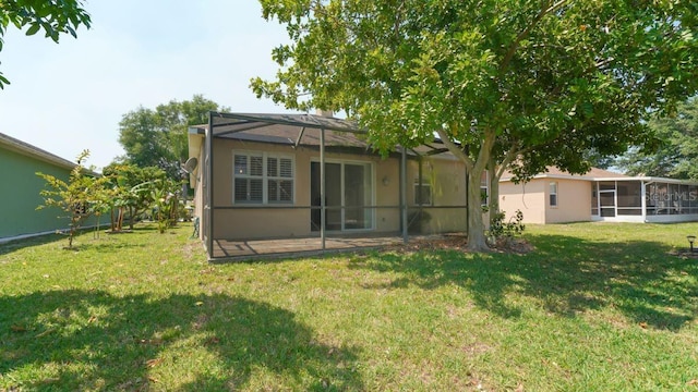 rear view of house featuring glass enclosure, a lawn, and stucco siding