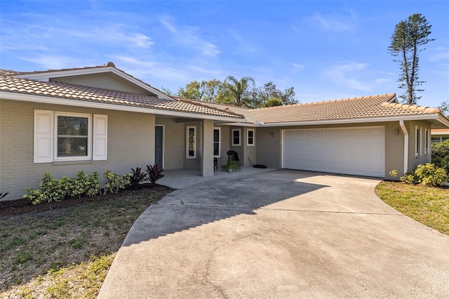 ranch-style house featuring driveway, brick siding, an attached garage, and a tiled roof