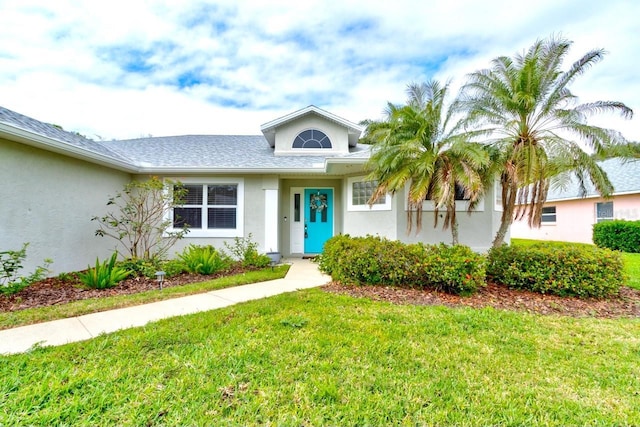 ranch-style house featuring a front lawn and stucco siding