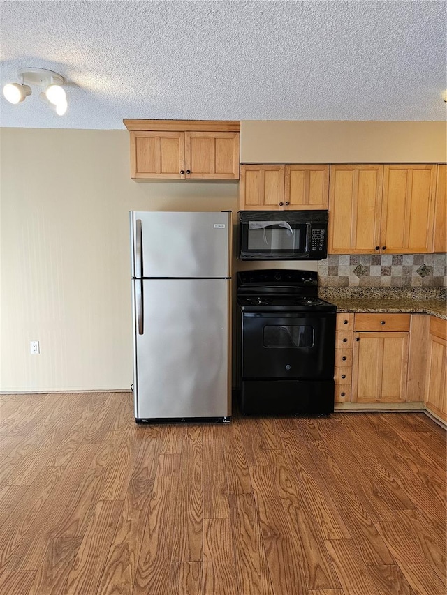 kitchen with a textured ceiling, black appliances, backsplash, and wood finished floors