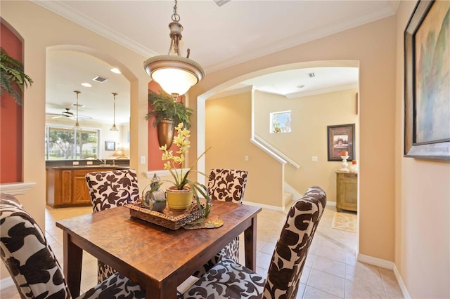 dining room featuring light tile patterned floors, baseboards, arched walkways, and crown molding