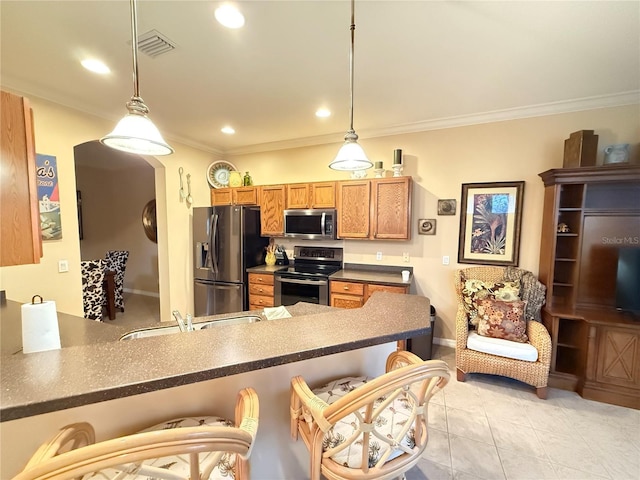 kitchen featuring dark countertops, hanging light fixtures, appliances with stainless steel finishes, a peninsula, and a kitchen bar