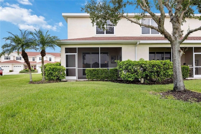 rear view of property with a sunroom, a lawn, and stucco siding