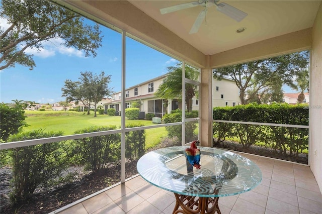 sunroom featuring ceiling fan and a residential view