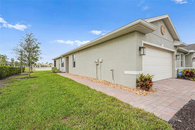 view of property exterior featuring a garage, decorative driveway, a lawn, and stucco siding