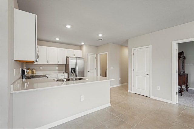 kitchen with light countertops, appliances with stainless steel finishes, white cabinets, a sink, and a peninsula