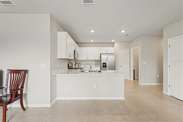 kitchen featuring stainless steel appliances, visible vents, light countertops, a sink, and a peninsula