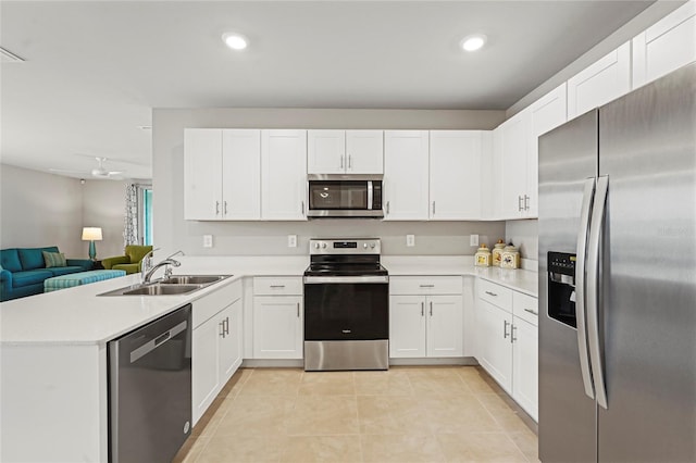 kitchen with light tile patterned floors, appliances with stainless steel finishes, open floor plan, a peninsula, and a sink