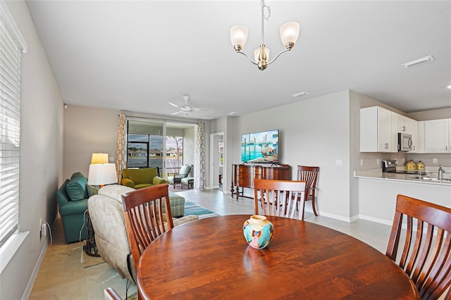 dining space with light tile patterned flooring, visible vents, baseboards, and ceiling fan with notable chandelier