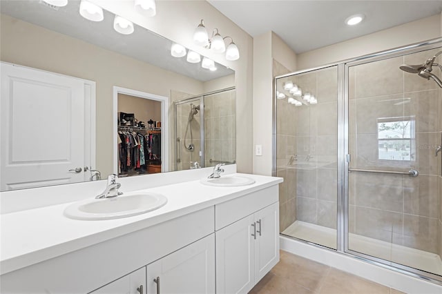 full bath featuring double vanity, a stall shower, a sink, and tile patterned floors