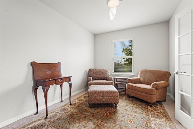 living area featuring carpet, a ceiling fan, and baseboards