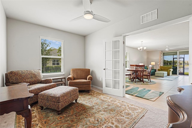 living area with ceiling fan with notable chandelier, french doors, visible vents, and tile patterned floors