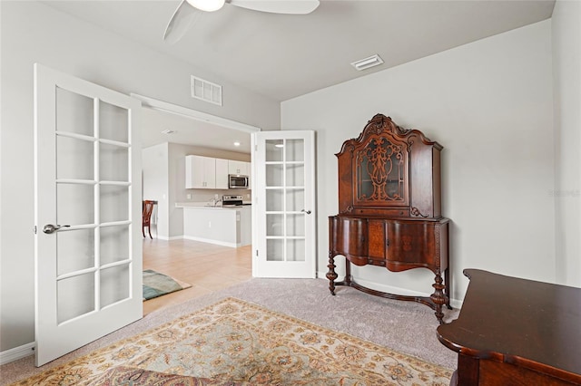 living area with french doors, light colored carpet, visible vents, a ceiling fan, and baseboards