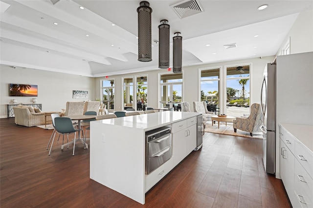 kitchen featuring visible vents, dark wood-type flooring, open floor plan, white cabinets, and a kitchen island