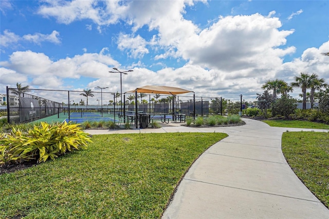 view of property's community featuring a yard, fence, and a tennis court