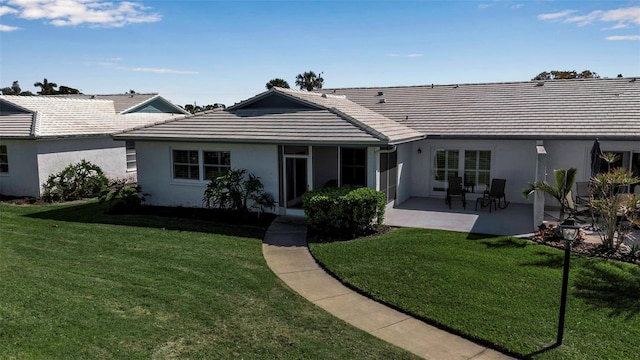 back of property with a yard, a patio, a tiled roof, and stucco siding