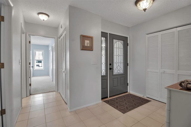 foyer entrance featuring light tile patterned floors, baseboards, and a textured ceiling