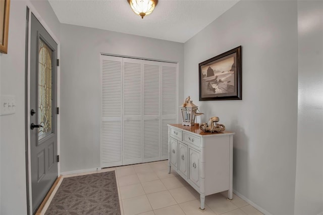 entryway featuring a textured ceiling, light tile patterned flooring, and baseboards