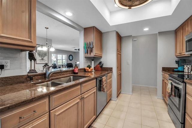 kitchen featuring appliances with stainless steel finishes, dark stone countertops, a sink, and decorative backsplash