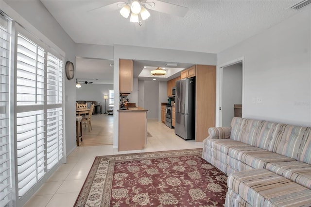 living room with visible vents, ceiling fan, a textured ceiling, and light tile patterned flooring