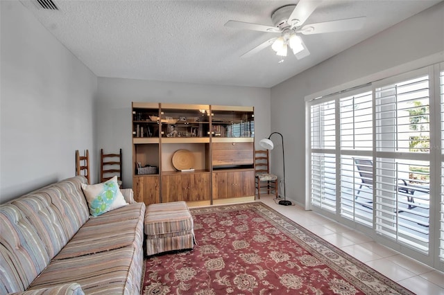 living room with a textured ceiling, visible vents, tile patterned flooring, and a ceiling fan