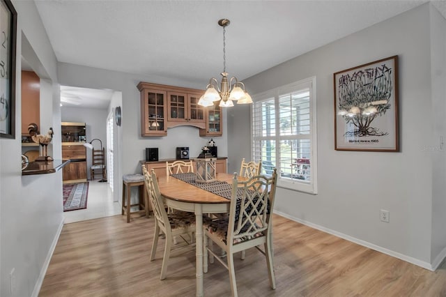 dining area featuring baseboards, light wood-type flooring, and an inviting chandelier