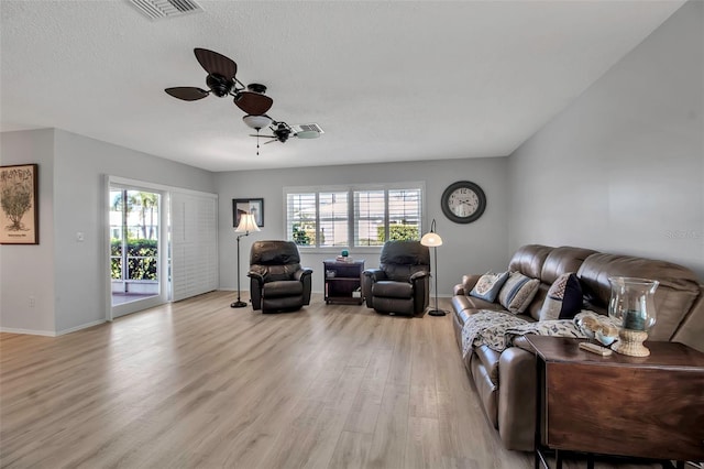 living area with light wood finished floors, plenty of natural light, visible vents, and a textured ceiling