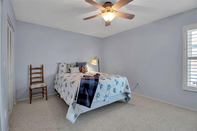 carpeted bedroom with a ceiling fan, a closet, and baseboards