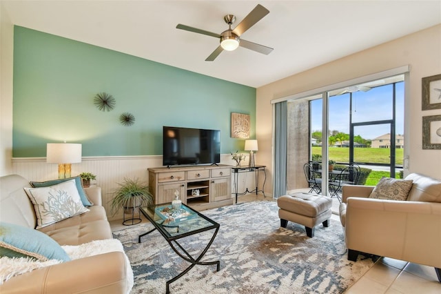 tiled living area featuring a wainscoted wall and a ceiling fan