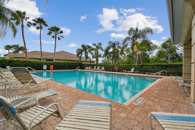 community pool with a patio area and fence