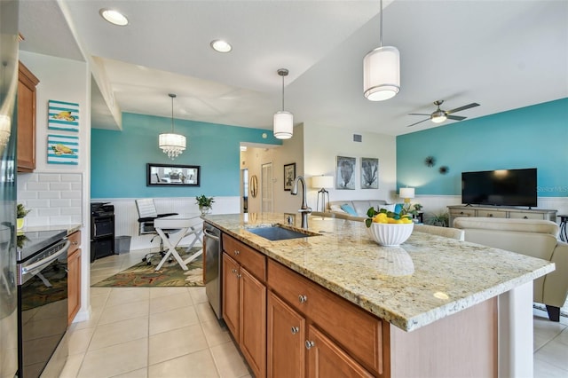 kitchen featuring light tile patterned floors, hanging light fixtures, appliances with stainless steel finishes, brown cabinetry, and a sink