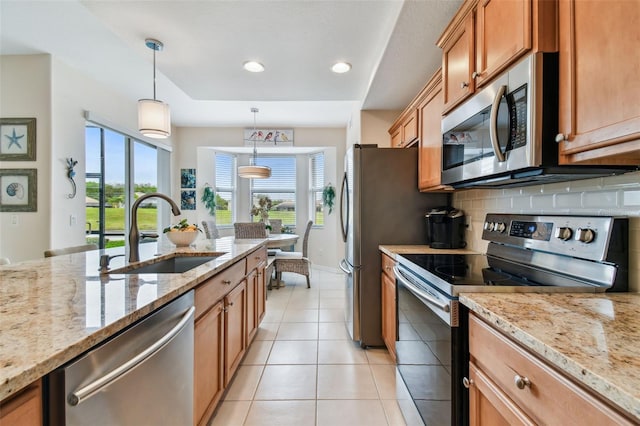 kitchen with light tile patterned flooring, stainless steel appliances, a sink, tasteful backsplash, and decorative light fixtures