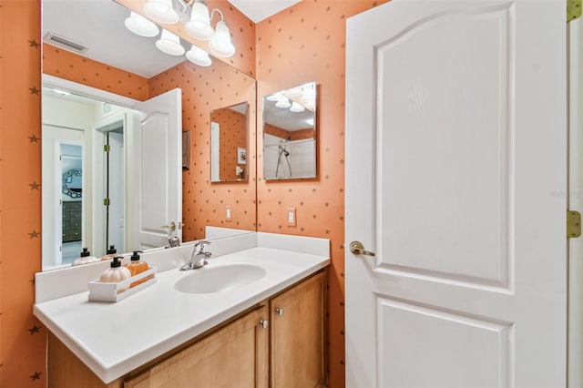 bathroom with vanity, visible vents, and wallpapered walls