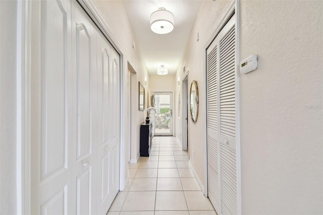 corridor featuring light tile patterned floors and baseboards